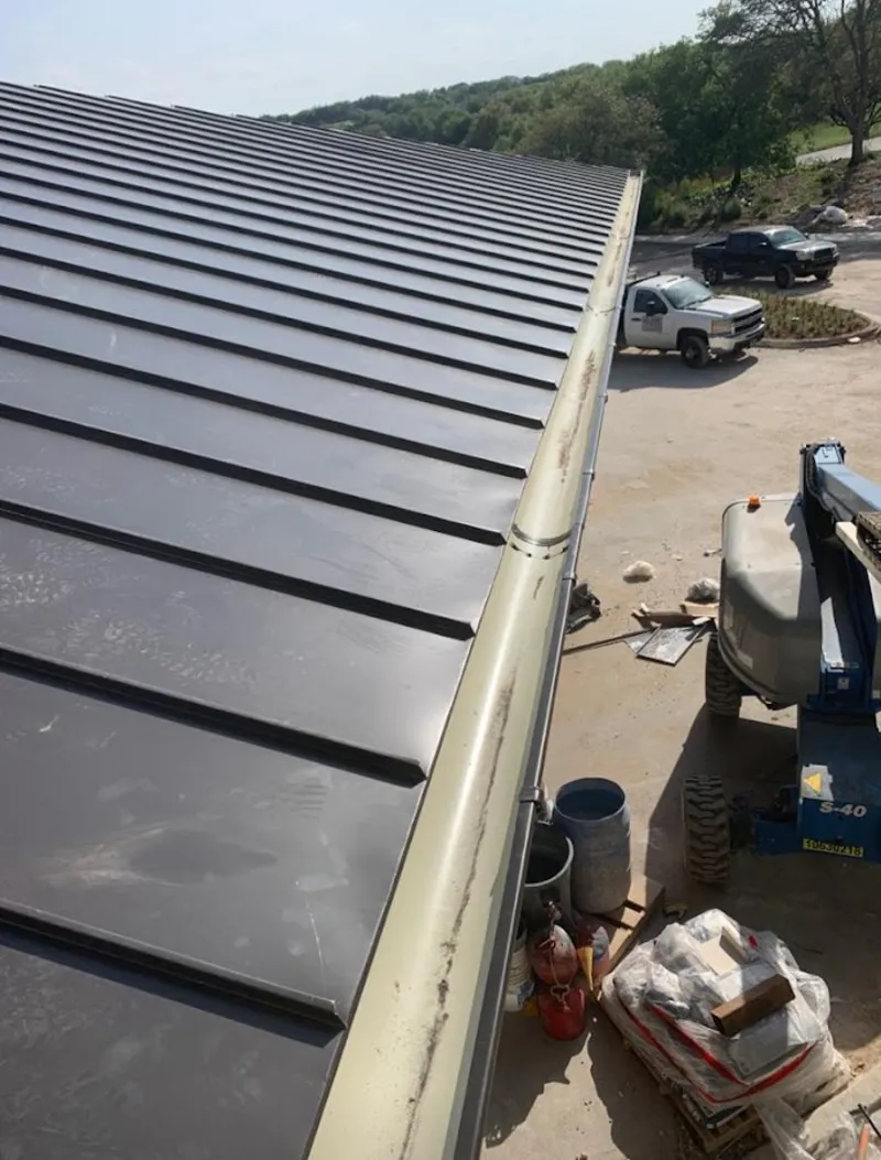 Standing seam panel and gutter detail on a metal roofing jobsite in Humble